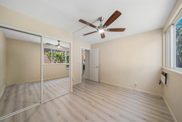 unfurnished bedroom featuring a closet, multiple windows, light wood-style flooring, and baseboards