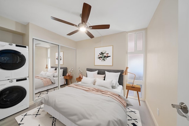 bedroom with stacked washer / drying machine, a closet, ceiling fan, and baseboards