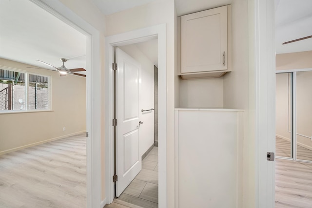 hall with baseboards and light wood-style floors