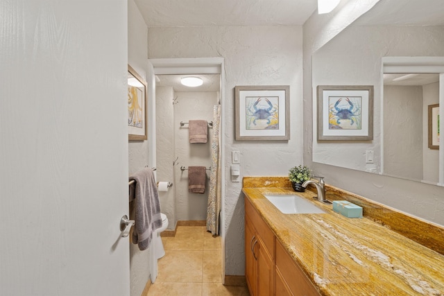 bathroom featuring a shower with curtain, a textured wall, vanity, and tile patterned floors