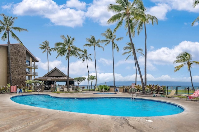 community pool with a gazebo, a patio area, fence, and a hot tub