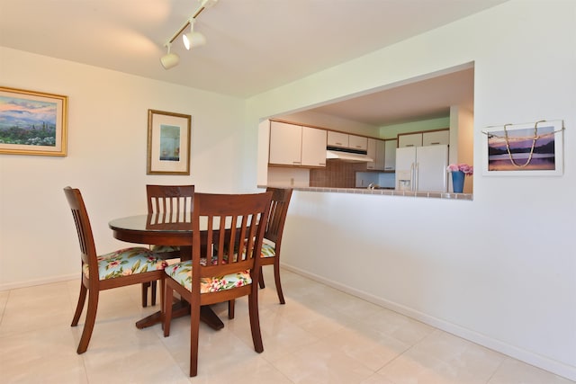 dining area with rail lighting and light tile patterned floors