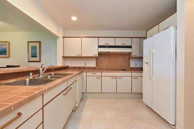 kitchen featuring white appliances, light tile patterned floors, tasteful backsplash, tile counters, and sink