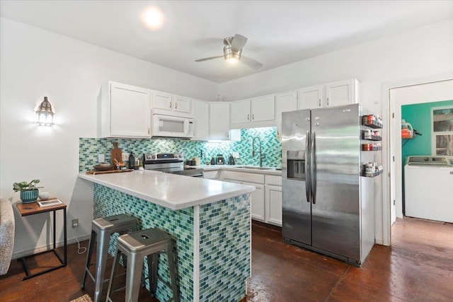 568 Hana Hwy Unit B, Paia, HI 96779 - kitchen with stainless steel appliances, washer / dryer, a sink, a peninsula, and backsplash