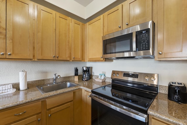 kitchen with sink, stainless steel appliances, and light stone countertops