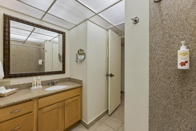 bathroom featuring a paneled ceiling, tile patterned floors, and vanity