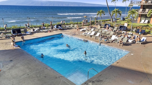 view of pool featuring a water view and a patio