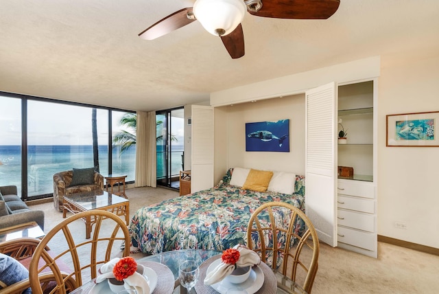 bedroom featuring access to exterior, baseboards, a wall of windows, and light colored carpet