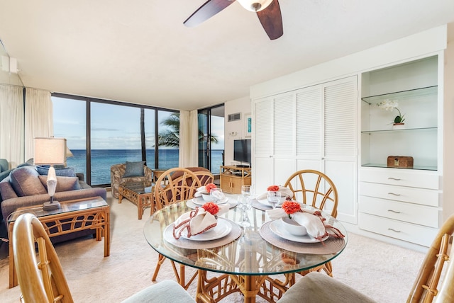 carpeted dining space featuring ceiling fan, visible vents, and a wall of windows