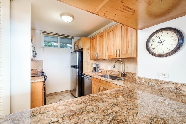 kitchen with light tile patterned floors, appliances with stainless steel finishes, light stone counters, sink, and tasteful backsplash