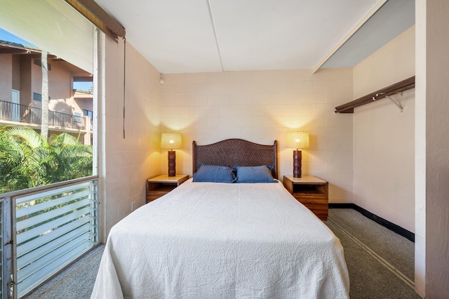 carpeted bedroom featuring concrete block wall and baseboards