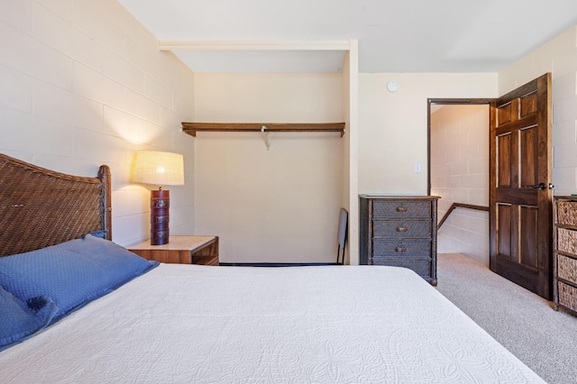 carpeted bedroom featuring a closet and concrete block wall