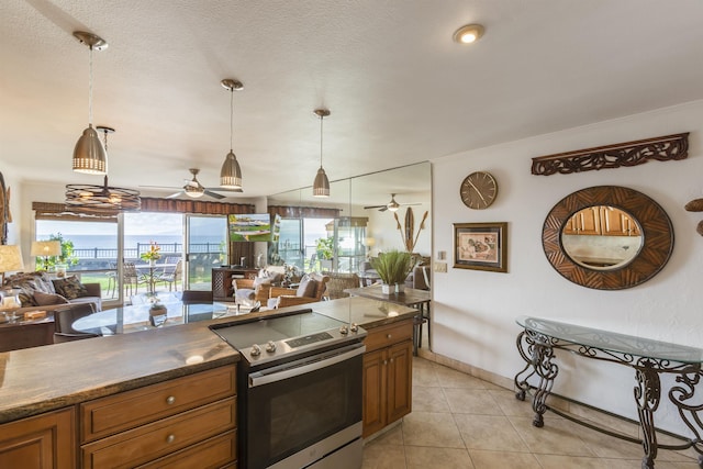 kitchen with pendant lighting, ceiling fan, light tile patterned floors, and stainless steel range with electric cooktop