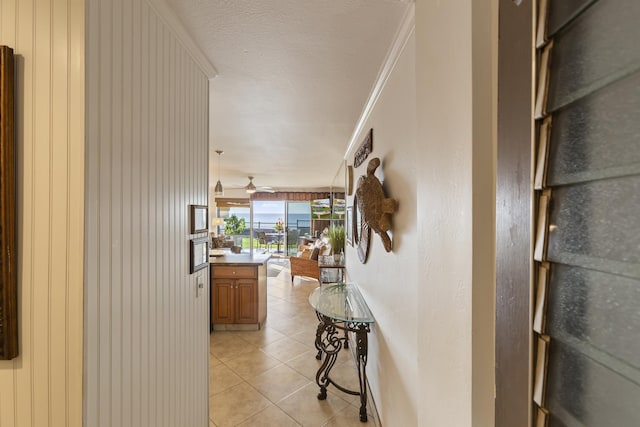 hall featuring a textured ceiling, light tile patterned floors, and crown molding