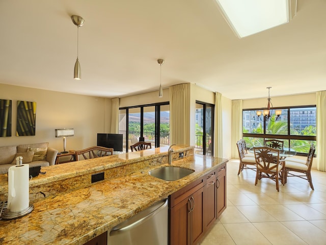 kitchen with sink, light stone counters, stainless steel dishwasher, a chandelier, and pendant lighting