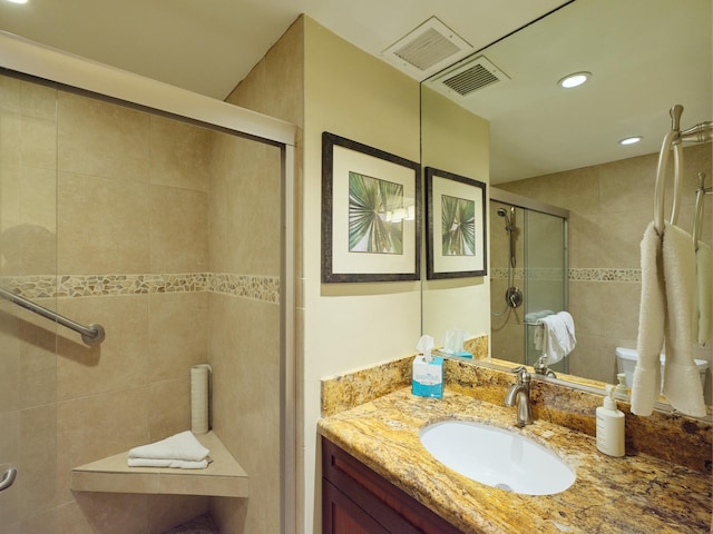 bathroom with a shower with door, vanity, and tile walls