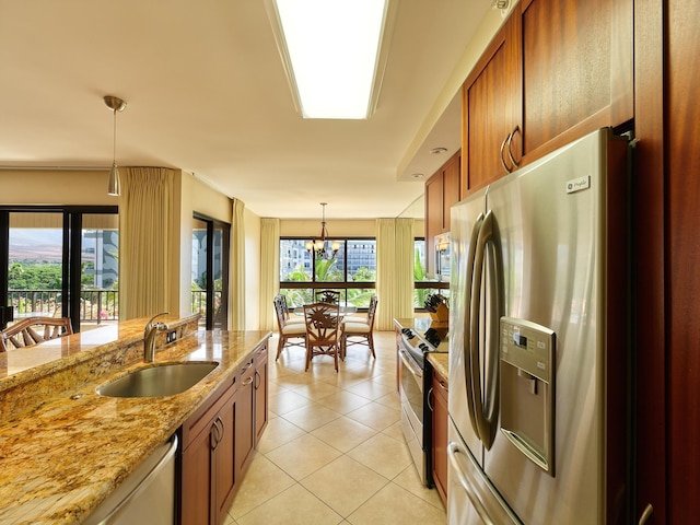 kitchen featuring light stone counters, pendant lighting, a notable chandelier, appliances with stainless steel finishes, and sink