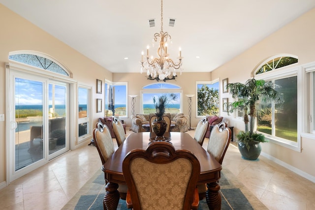 tiled dining room featuring a chandelier, a water view, and plenty of natural light