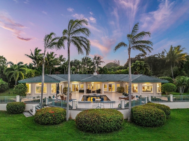 back house at dusk with a yard and a patio