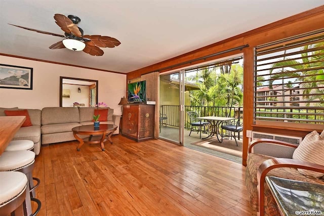 living room featuring a wall unit AC, hardwood / wood-style floors, a ceiling fan, and crown molding