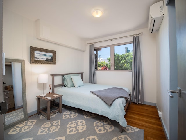 bedroom with a wall mounted air conditioner and dark hardwood / wood-style flooring