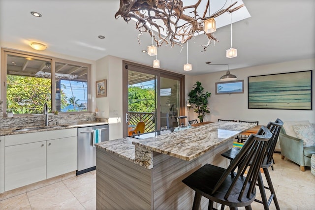 kitchen featuring light tile patterned floors, sink, dishwashing machine, and white cabinetry