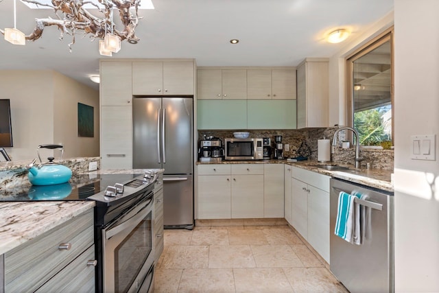 kitchen with tasteful backsplash, cream cabinetry, stainless steel appliances, light stone countertops, and sink