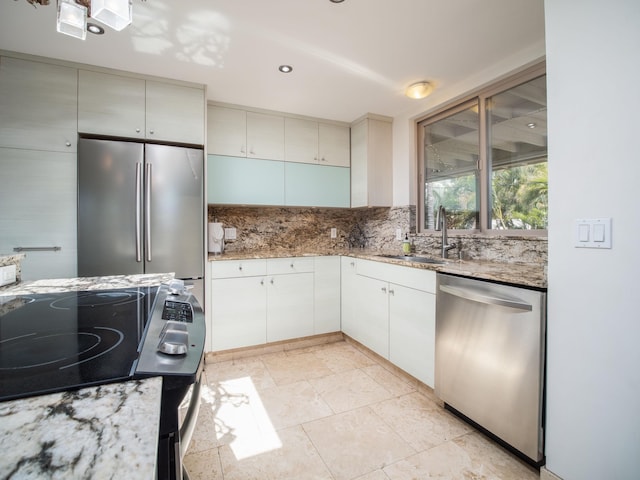 kitchen featuring light tile patterned floors, appliances with stainless steel finishes, sink, tasteful backsplash, and light stone counters