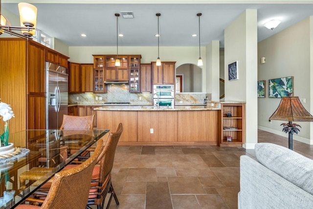 1387 Hihimanu St Unit 16, Kihei, HI 96753 - kitchen featuring light stone counters, decorative light fixtures, kitchen peninsula, stainless steel appliances, and backsplash