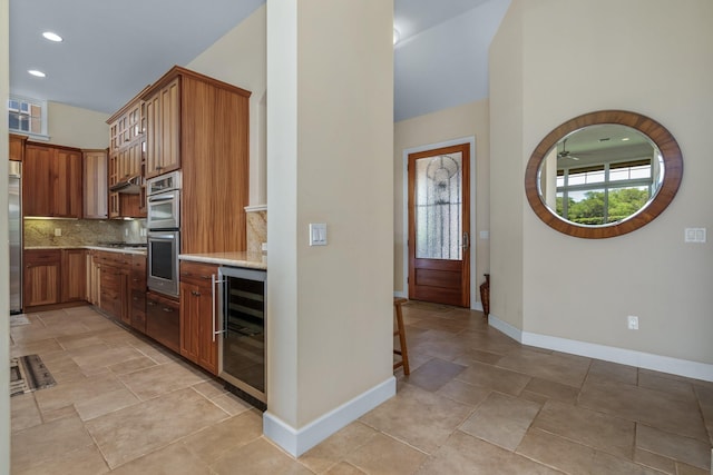 1387 Hihimanu St Unit 16, Kihei, HI 96753 - kitchen featuring appliances with stainless steel finishes, a towering ceiling, beverage cooler, decorative backsplash, and light stone counters