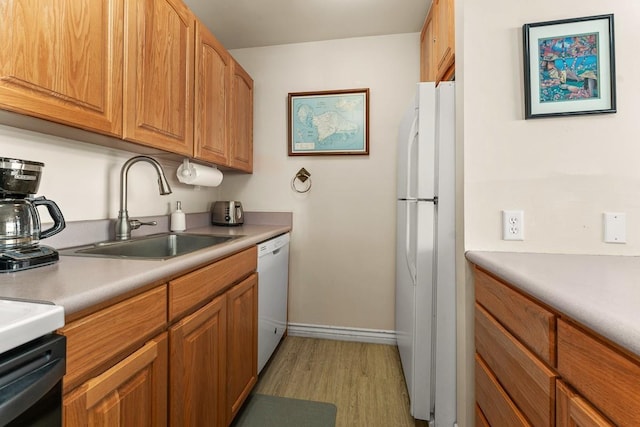 kitchen with light wood-type flooring, white appliances, and sink