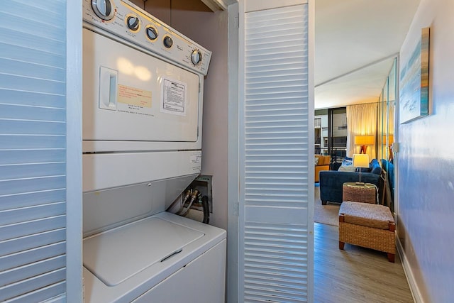 clothes washing area featuring wood-type flooring and stacked washing maching and dryer