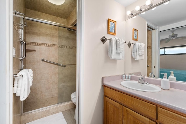 bathroom with toilet, ceiling fan, an enclosed shower, and vanity