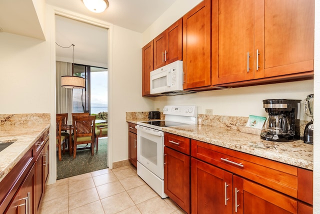 kitchen featuring light stone counters, pendant lighting, light tile patterned flooring, and white appliances