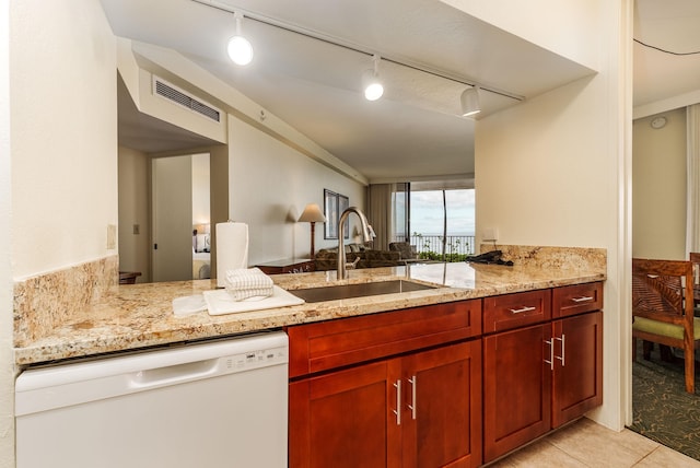 kitchen with light tile patterned flooring, kitchen peninsula, light stone countertops, white dishwasher, and sink