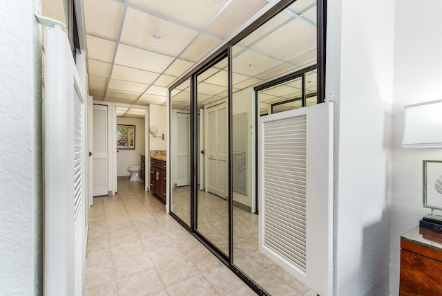 hallway featuring a paneled ceiling and light tile patterned floors