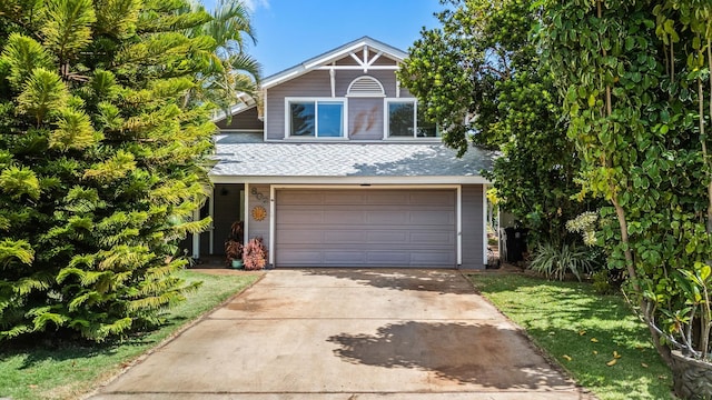 traditional home featuring roof with shingles, driveway, and an attached garage