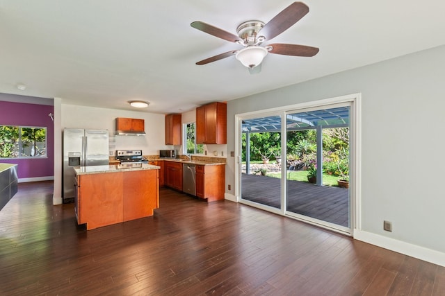 kitchen featuring baseboards, a kitchen island, appliances with stainless steel finishes, and dark wood-style flooring