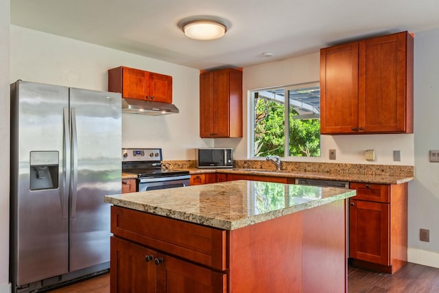 kitchen featuring dark wood-style floors, appliances with stainless steel finishes, a sink, a kitchen island, and under cabinet range hood