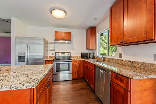 kitchen with stainless steel appliances, dark wood-type flooring, a sink, and light stone counters