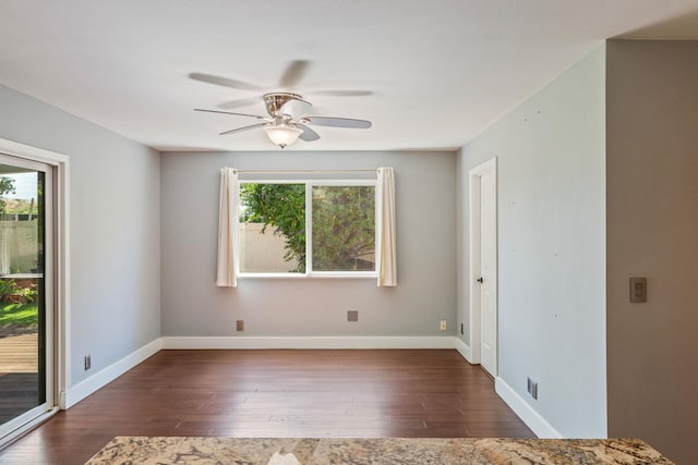 unfurnished room featuring baseboards, dark wood finished floors, and a ceiling fan