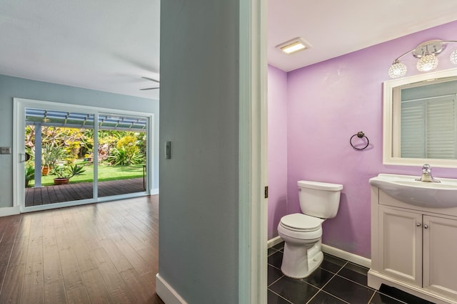 bathroom featuring toilet, baseboards, a ceiling fan, and vanity