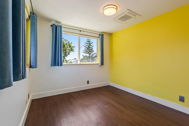 spare room with baseboards, visible vents, and dark wood-style flooring