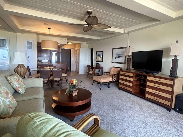 carpeted living room with ceiling fan and beamed ceiling