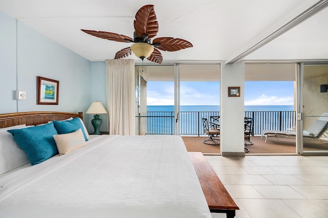 bedroom with expansive windows, a water view, and multiple windows