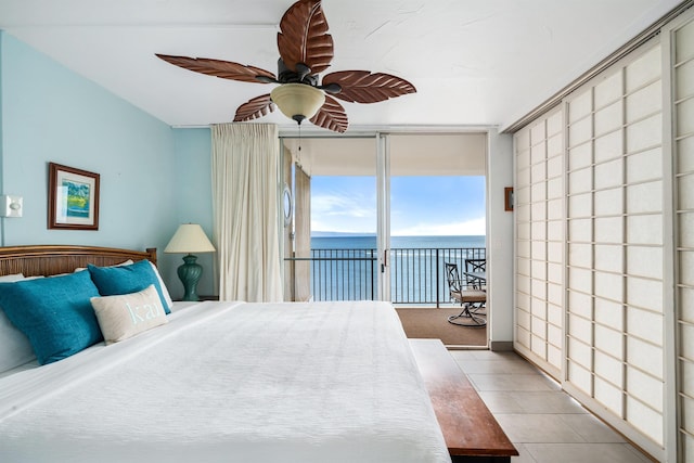 bedroom featuring ceiling fan, expansive windows, light tile patterned flooring, access to outside, and a water view