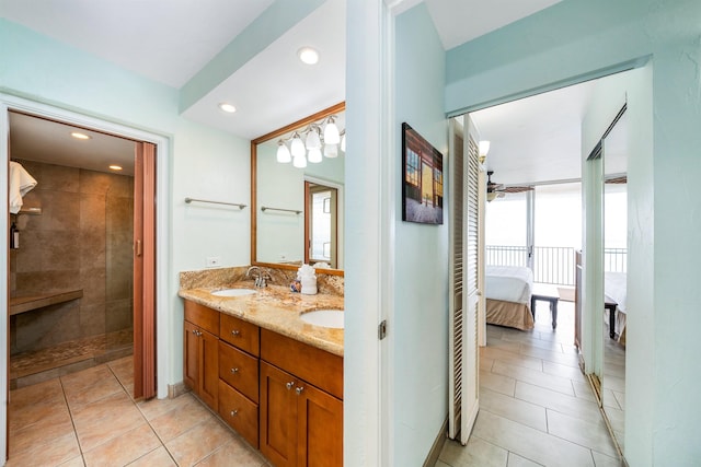 bathroom featuring tile patterned floors, vanity, expansive windows, and a tile shower