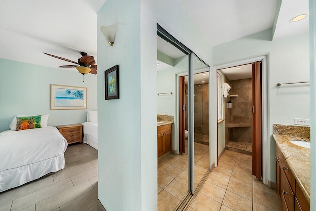 bedroom featuring ensuite bathroom, sink, ceiling fan, light tile patterned floors, and a closet