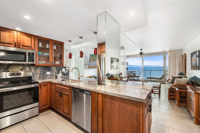 kitchen with kitchen peninsula, appliances with stainless steel finishes, a water view, and sink