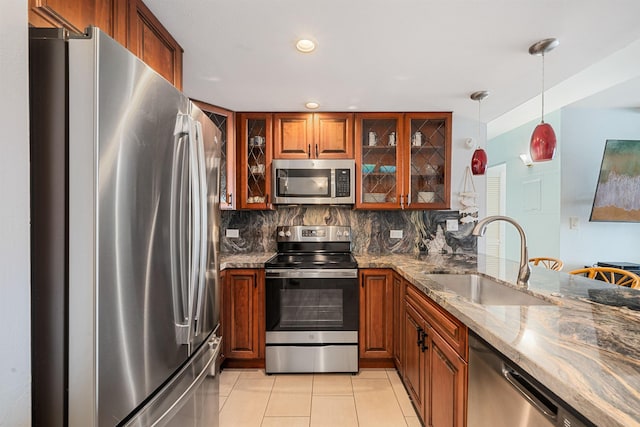 kitchen with hanging light fixtures, sink, light stone countertops, appliances with stainless steel finishes, and tasteful backsplash